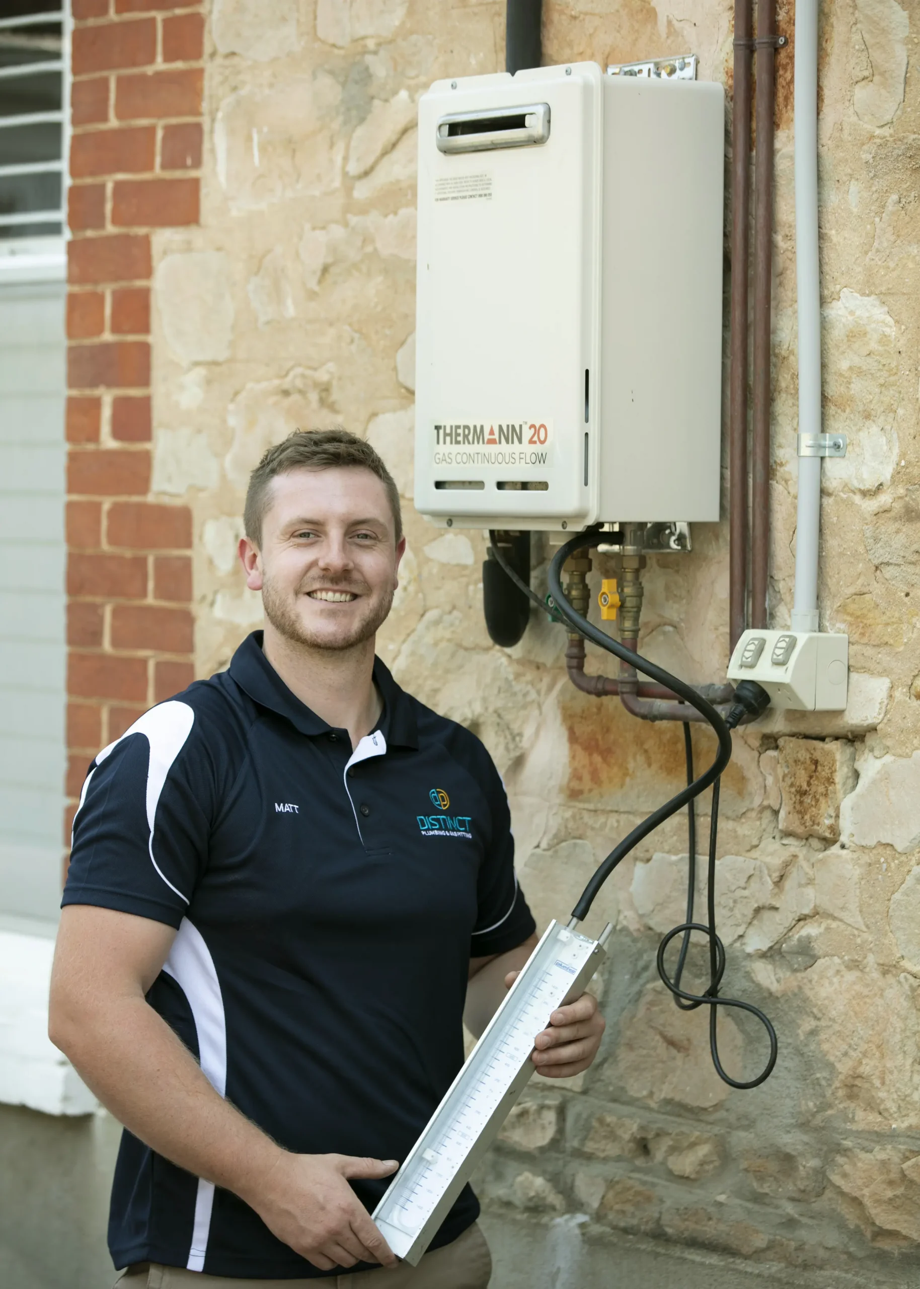 A plumber conducting maintenance check on hot water systems in a residential property.